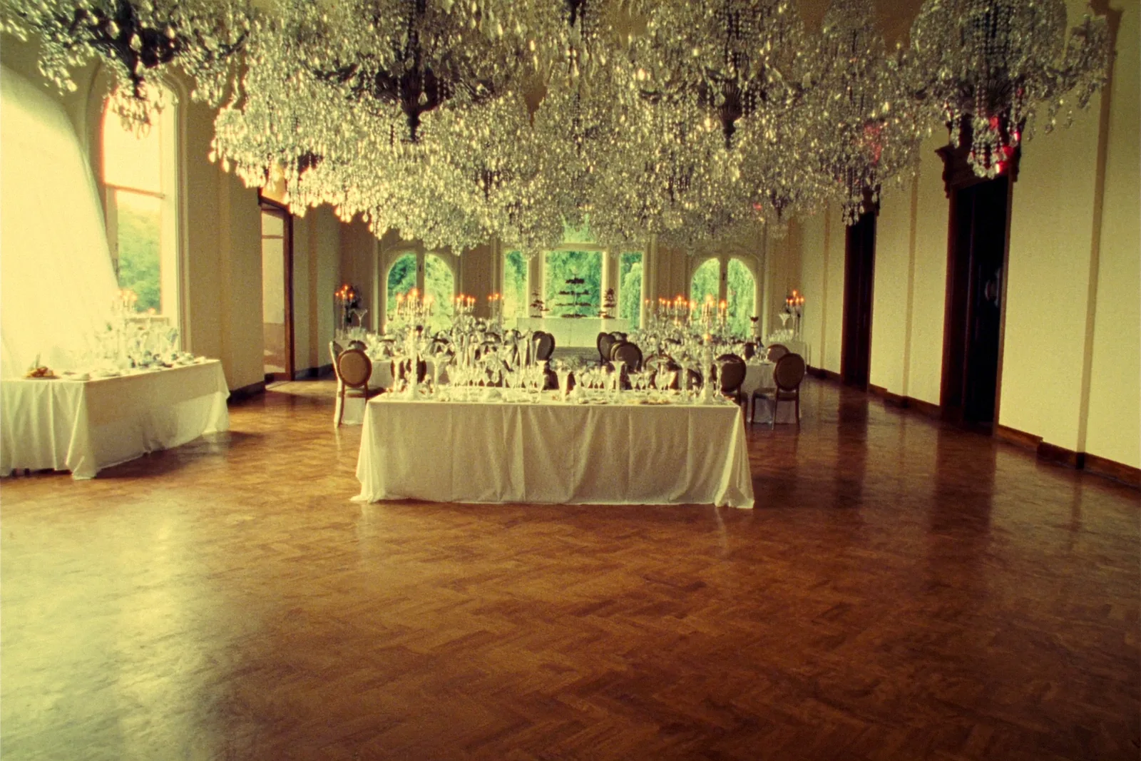 A luxury ballroom with crystal chandeliers reflected in a polished parquet floor