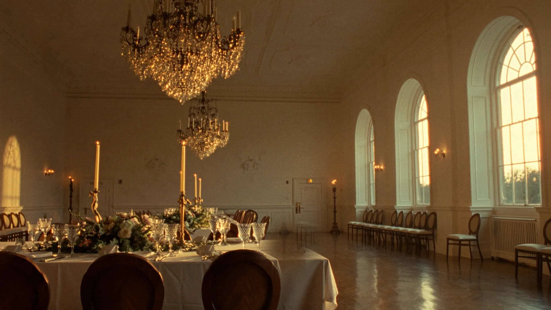 A grand heritage ballroom dressed for a wedding reception in warm golden light